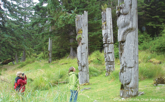 お墓に建てられたトーテムポールを見上げる訪問者